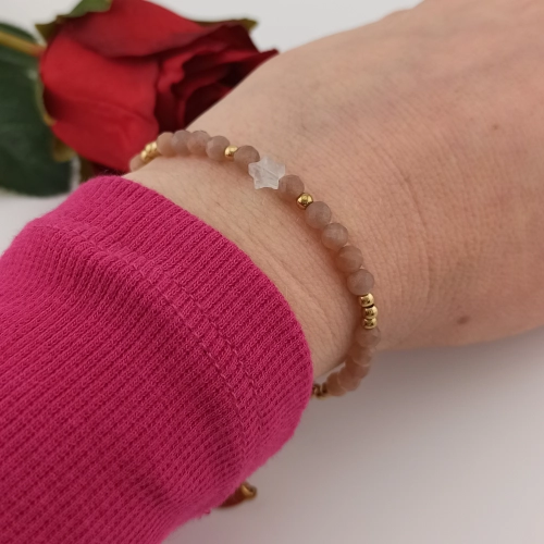 Delikatna biżuteria z jasnymi kamieniami naturalnymi i subtelną gwiazdką elegancko zaprezentowana na kobiecym ręku